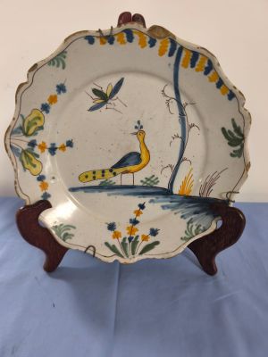 a plate with a peacock on it sitting on a table