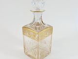 a clear glass bottle with a gold decoration on it