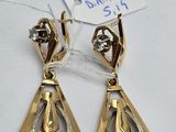 une paire de boucles d'oreilles dorées ornées de diamants sur fond blanc