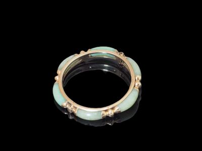 une image représentant une bague en or et en jade sur fond noir