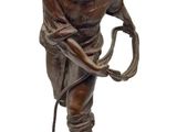 bronze statue of a man with a whip and a hat
