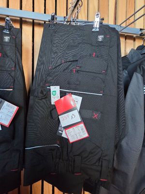 three pairs of black pants hanging on a rack in a store