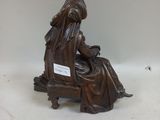 a bronze statue of a woman sitting on a chair