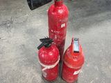 three fire extinguisors sitting on the ground next to each other