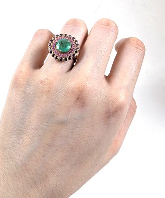 la main d'une personne tenant une bague sertie d'une pierre verte