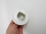 a person holding a white cup and saucer on a white surface