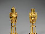 paire de vases plaqués or reposant sur des socles en marbre, posés sur un socle gris