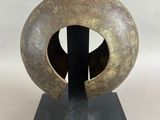 une photo d'une sculpture représentant un objet circulaire posé sur un socle
