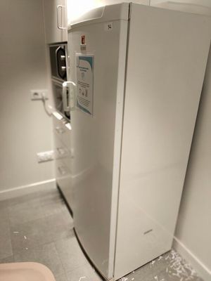 un réfrigérateur blanc et des toilettes dans une petite pièce