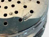 a metal strainer with holes in it on a white surface