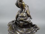 une statue antique en bronze représentant une femme assise sur un coquillage