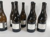 six bottles of wine are lined up in a row on a white surface