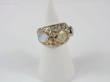 une bague en or et en argent ornée de lunes, posée sur un présentoir blanc pour bagues