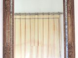 un miroir accroché au mur, avec un rideau derrière