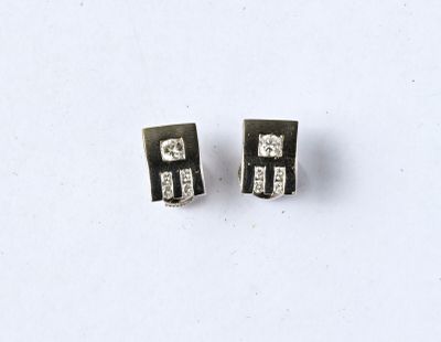 une paire de boucles d'oreilles à clous en diamant noir et blanc posées sur un fond blanc
