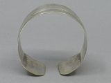 silver cuff bracelet with curved design on a plain surface