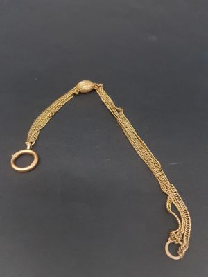 a close up of a gold chain bracelet with a circular clasp