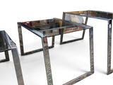 three glass tables with metal legs on a white surface
