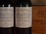two bottles of red wine sitting on top of a wooden table