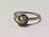 une bague sertie d'un diamant, posée sur une surface blanche