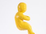 a yellow figurine of a baby sitting on a white surface