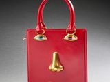 a close up of a red purse with a gold nose on it