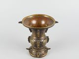 a bronze vase with a bird on it on a white surface