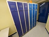 Plusieurs casiers bleus sont alignés dans le couloir d'un immeuble