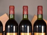 four bottles of red wine are lined up on a table