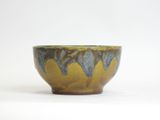 a brown and blue bowl sitting on a white surface