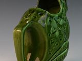 a green vase that has a leaf design on it