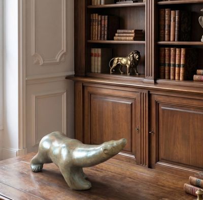 a statue of a bear on a table in front of a bookshelf