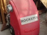a red machine that is sitting in front of a pile of wood