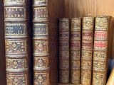 Plusieurs vieux livres sont empilés sur une étagère en bois dans une bibliothèque