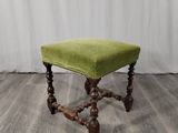 un tabouret rembourré vert posé sur un parquet