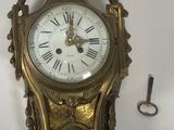a clock hanging on the wall with a key in front of it