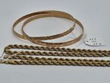 deux chaînes en or et un bracelet en or posés sur une surface blanche