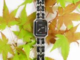 a black and white watch sitting on a chain bracelet