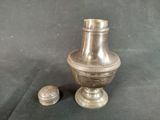 a silver vase and salt shaker sitting on a table