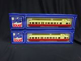 two boxes of toy trains sitting on top of a black surface