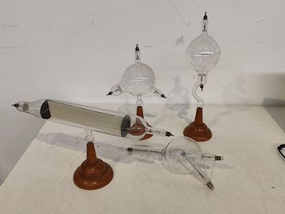 trois lampes en verre posées sur une table, avec un stylo et un crayon