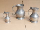 trois vases en argent posés par terre les uns à côté des autres