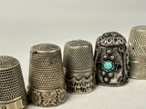 several antique thimbles are lined up in a row on a white surface