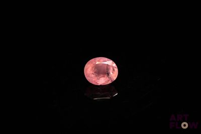 a close up of a pink diamond on a black surface