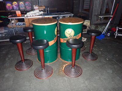 quatre fûts verts et des tabourets dans un garage