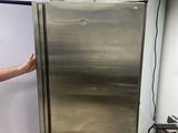 a man standing next to a stainless steel refrigerator in a kitchen