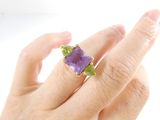 someone is holding a ring with a purple stone on it