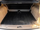 the back of a white van with its trunk open and a black floor mat in the trunk