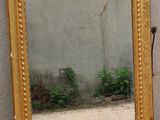 a mirror sitting on the ground next to a vase