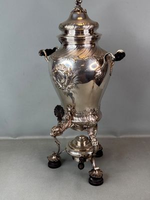 une urne ancienne en métal argenté, posée sur un socle, sur une table